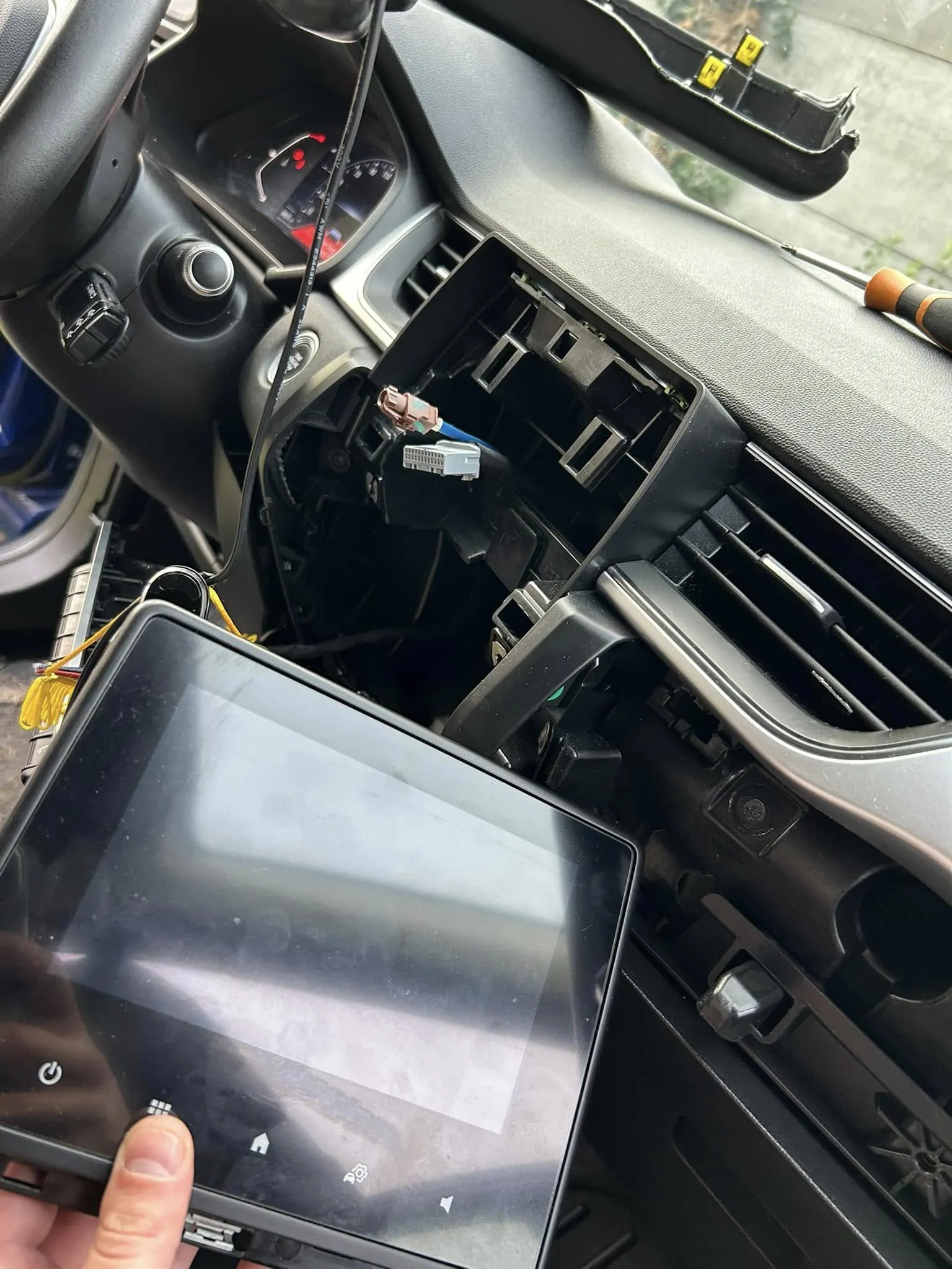 Cyfrowy zestaw zegarów w samochodzie Dacia, widoczny zza kierownicy.